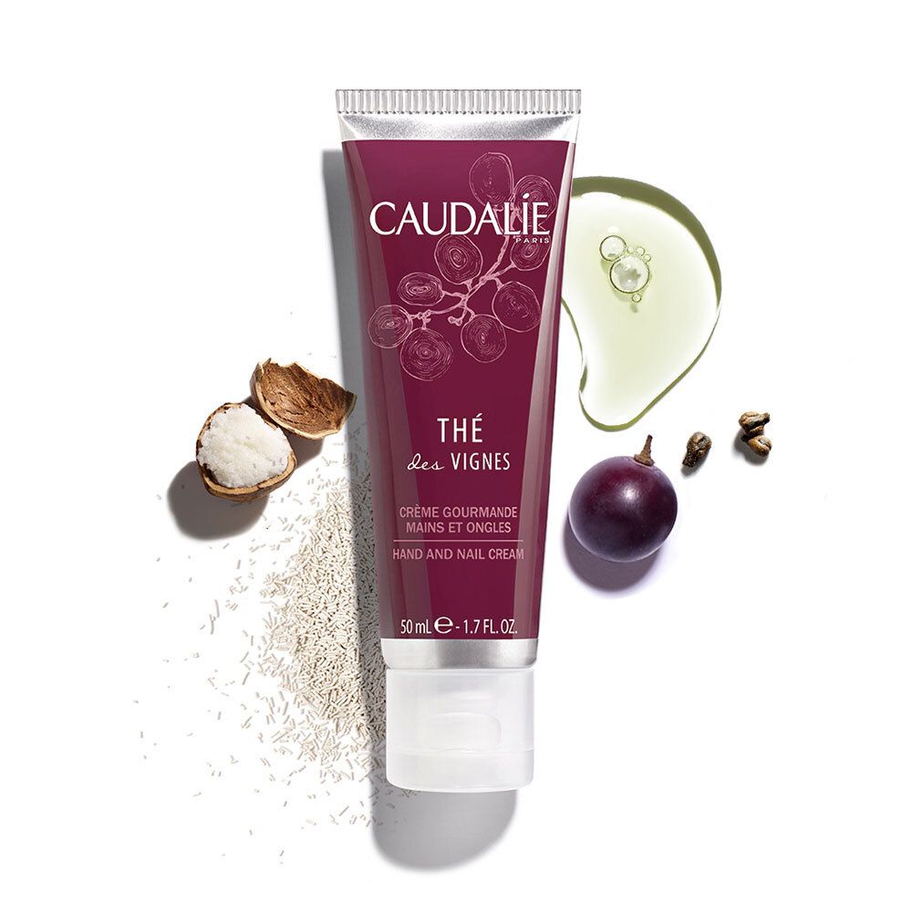 Tubo di crema viola con tappo argentato. Accanto: uva, olio, noci, semi. Scritta: CAUDALIE, Thé des Vignes. 50 ml.