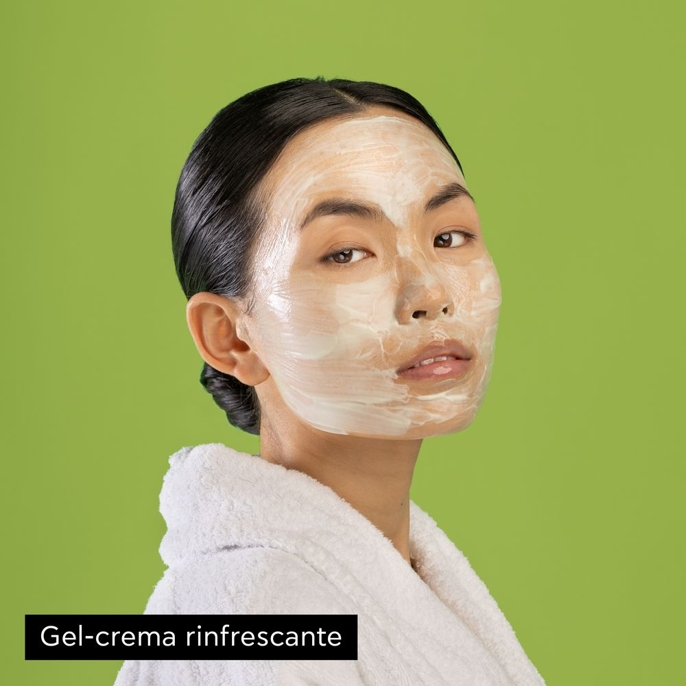 Donna con maschera viso. Crema sul viso, sfondo verde.