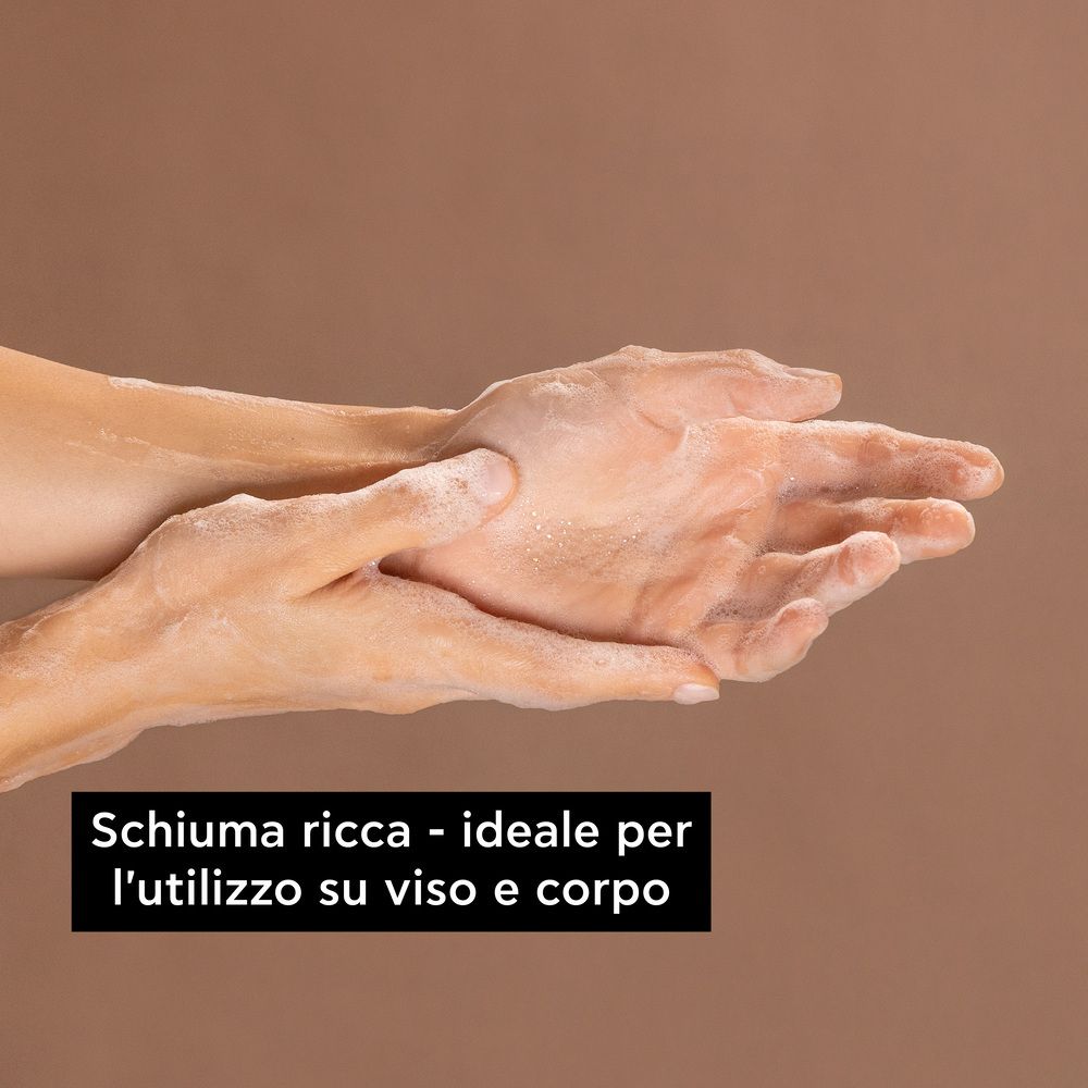 Mani con schiuma. Testo: Schiuma ricca, ideale per viso e corpo.