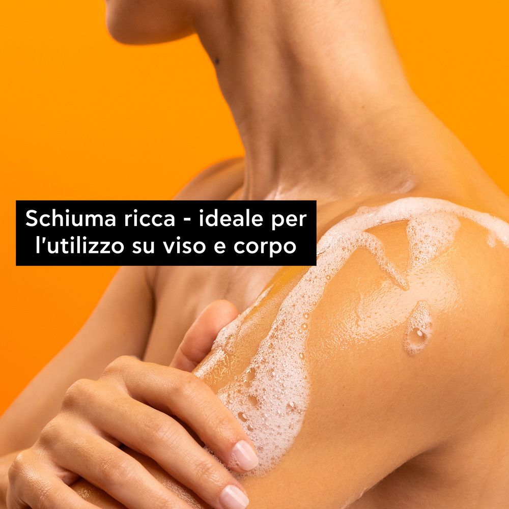 Persona con schiuma sulla spalla. Testo: 'Schiuma ricca - ideale per l'utilizzo su viso e corpo'.
