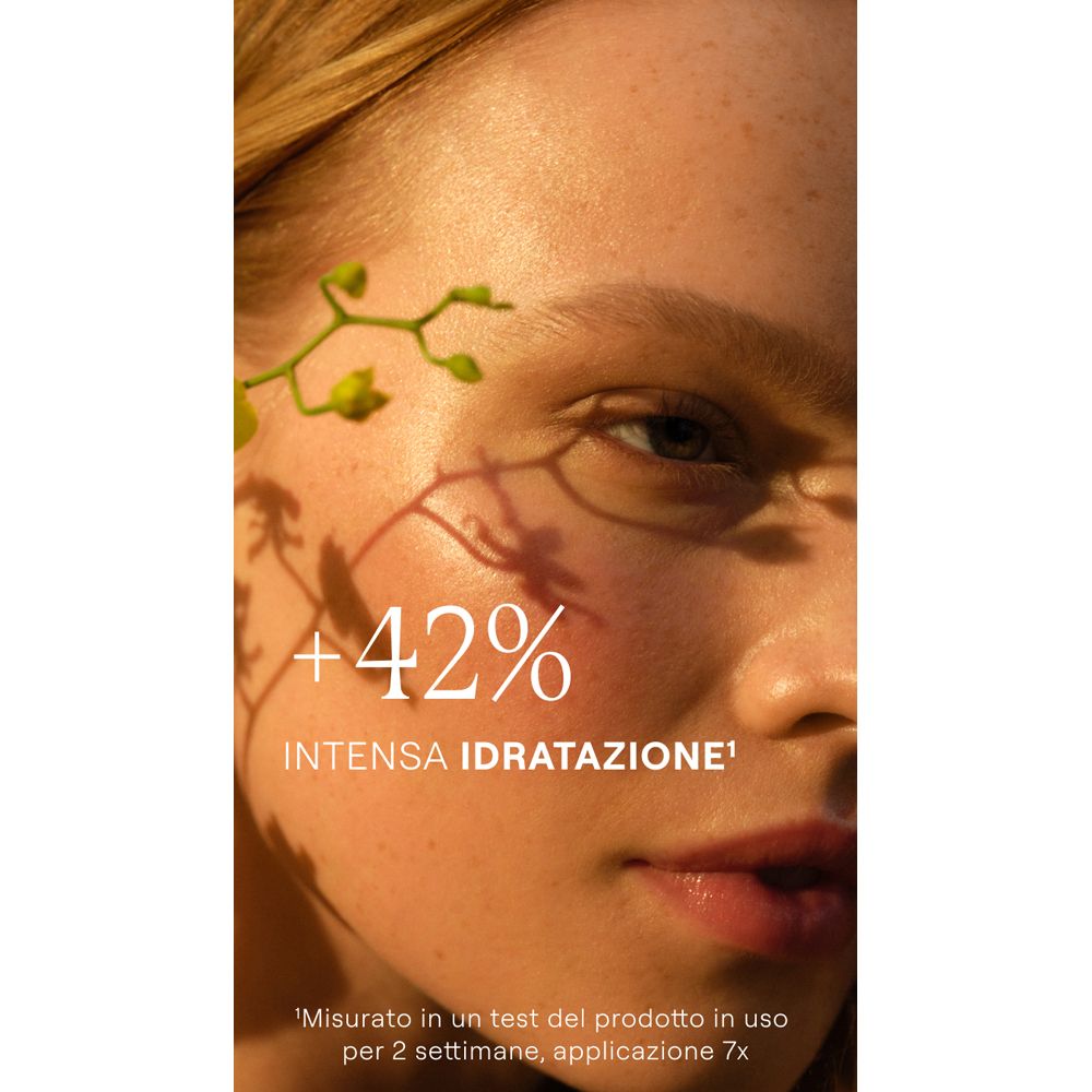 Volto di donna con ombre. Testo: +42% idratazione intensa. Sfondo: piante.