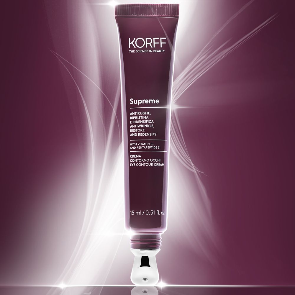 Tubo di crema contorno occhi KORFF Supreme. Rosso scuro, applicatore argento. Testo: antirughe, ridensificante, con vitamina B5. Effetti luce.