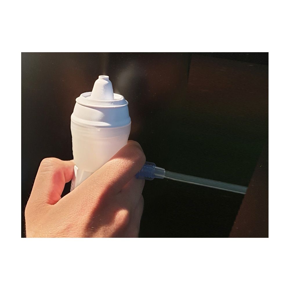 Persona che tiene in mano una doccia nasale bianca. Una sottile nebulizzazione esce dall'ugello. Un tubo è collegato.