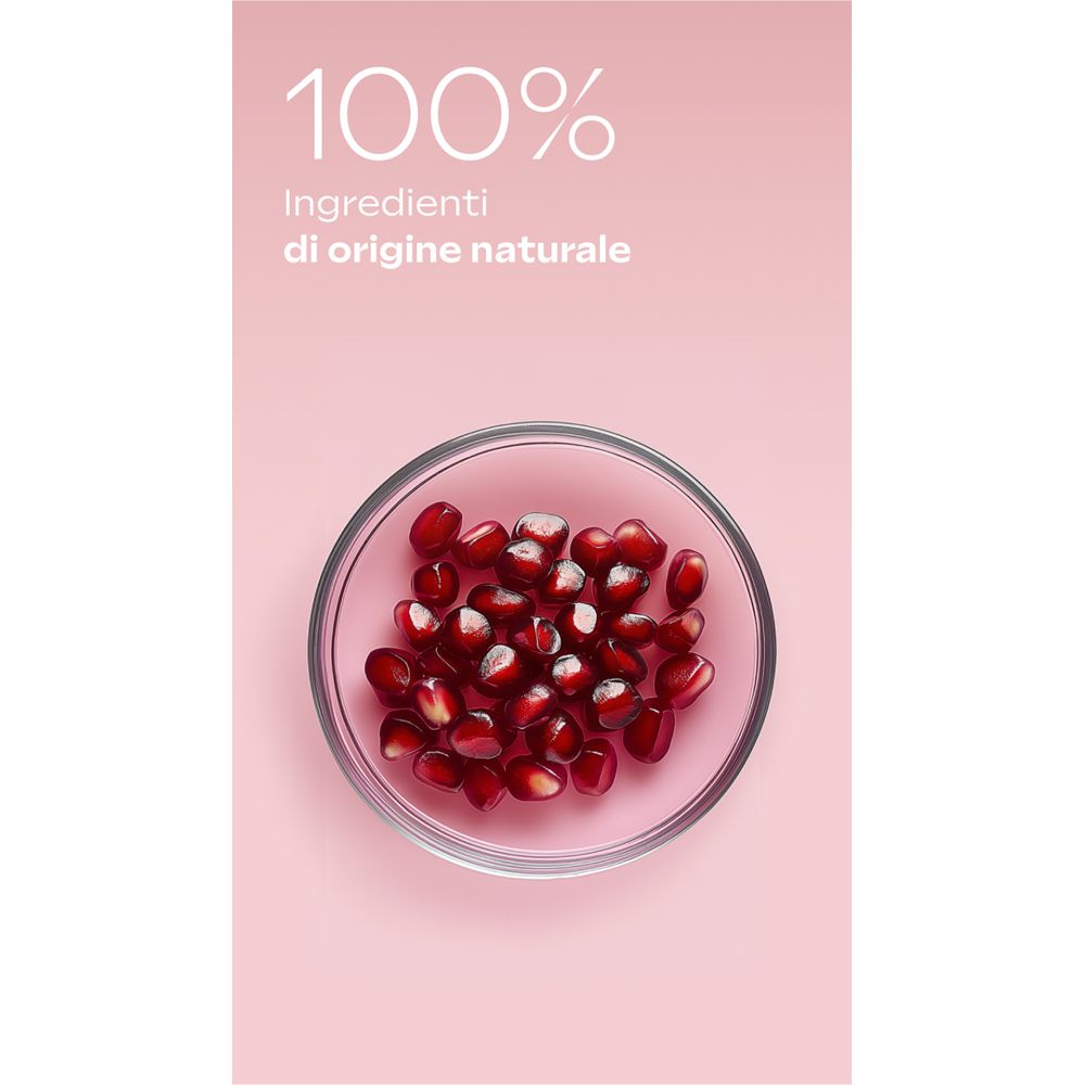 Sfondo rosa con ciotola di vetro piena di semi di melograno. Testo: 100% ingredienti di origine naturale.