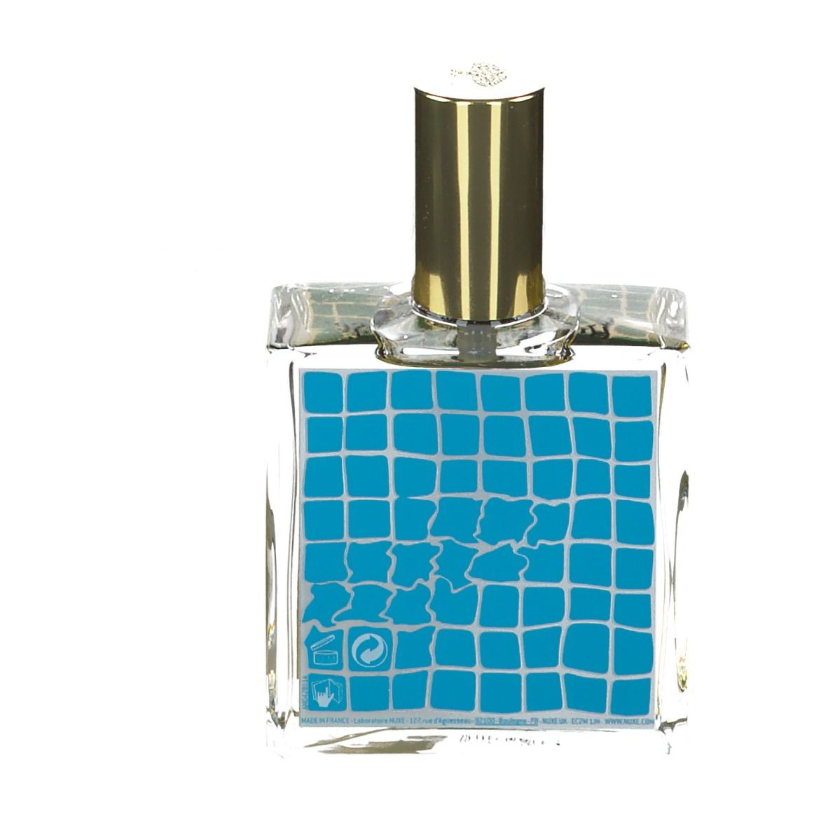 Flacone in vetro trasparente con tappo dorato. Etichetta blu con motivo quadrato e simboli.