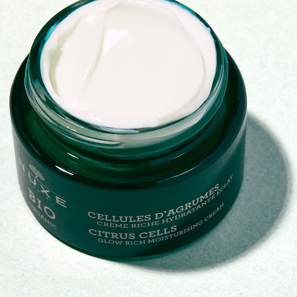 Vaso di crema verde aperto. Crema bianca visibile. Scritta: NUXE BIO, CELLULES D'AGRUMES, CITRUS CELLS, GLOW RICH MOISTURISING CREAM.