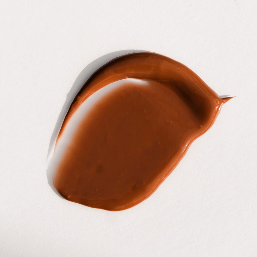 Liquido marrone su sfondo bianco. Il liquido è spalmato.