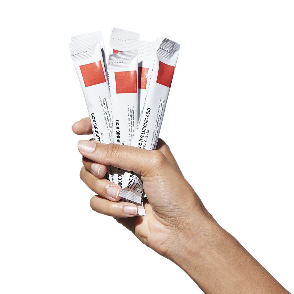 Mano che tiene diversi stick. Scritto: Pure Drink Collagen & Hyaluronic Acid. Striscia rossa. Marchio: FaceD.