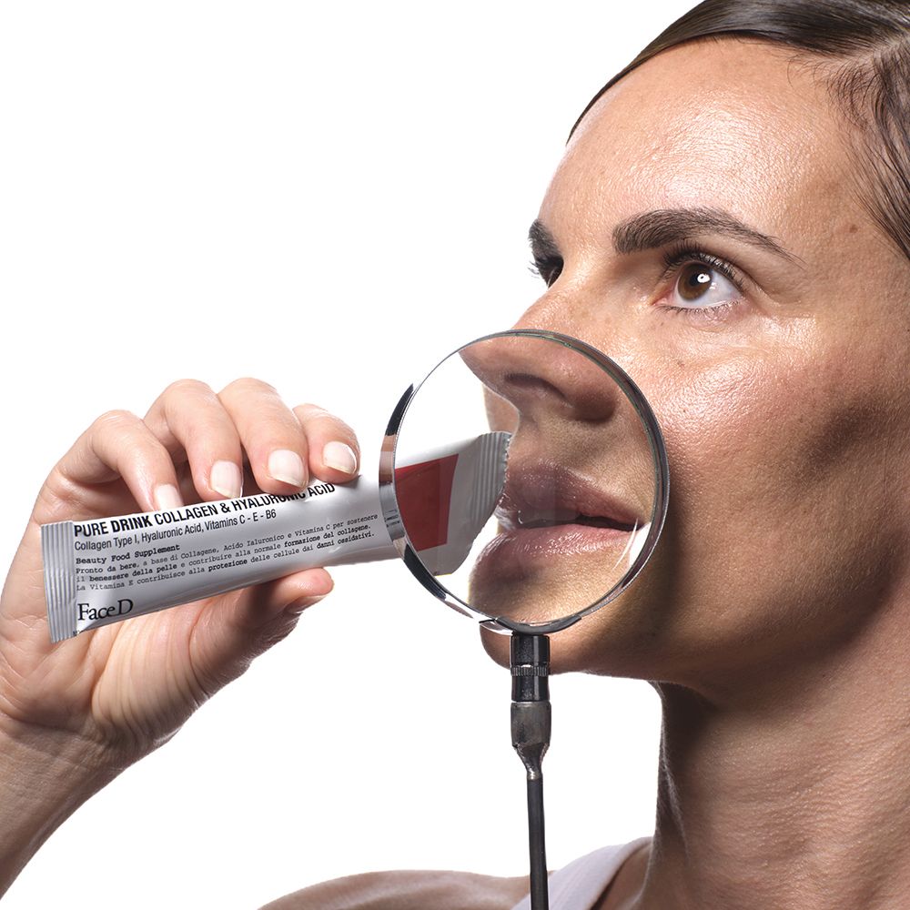 Donna con lente d'ingrandimento. Stick con scritto: Pure Drink Collagen & Hyaluronic Acid. Marchio: FaceD. Striscia rossa.