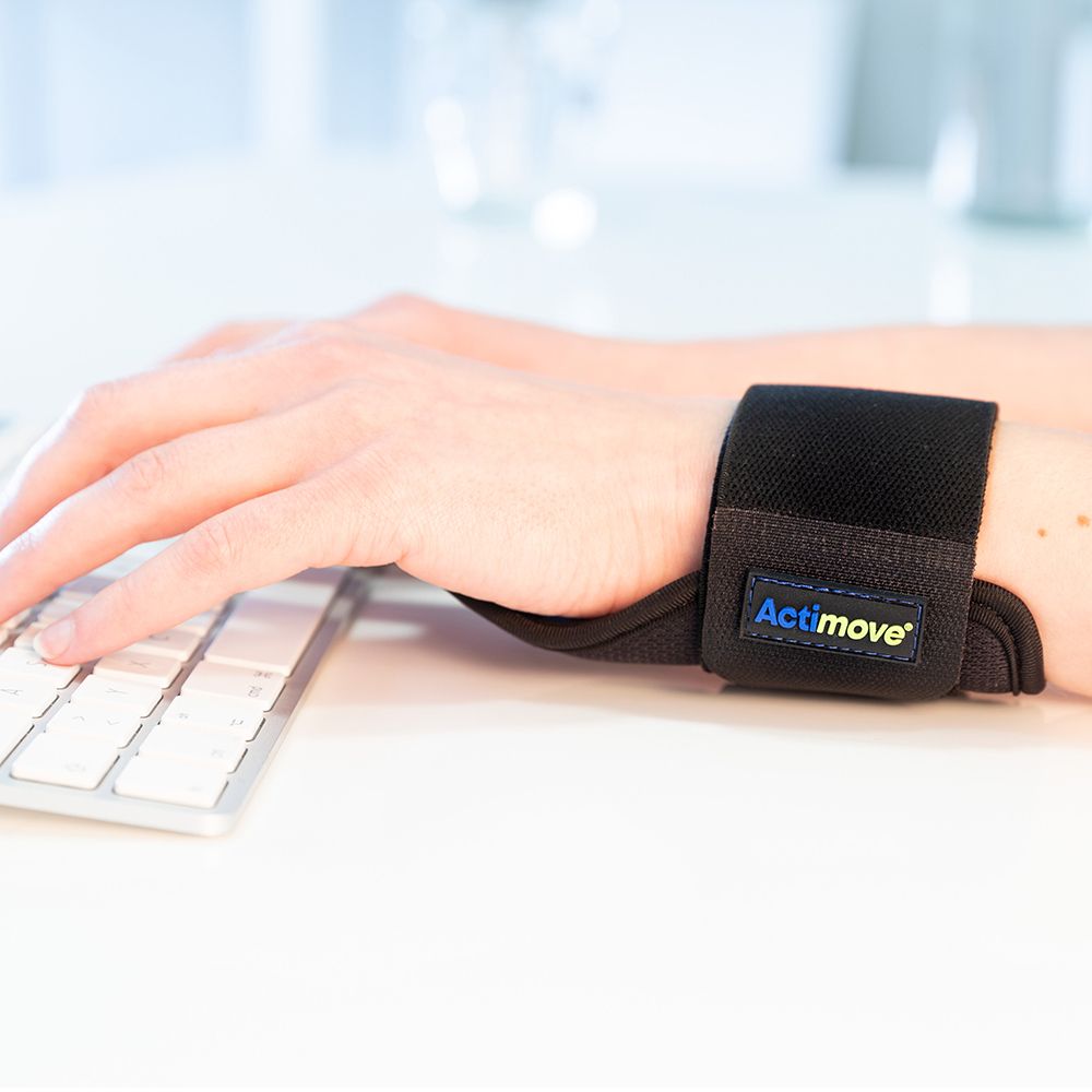 Persona che digita con tutore per polso nero. Logo Actimove visibile.