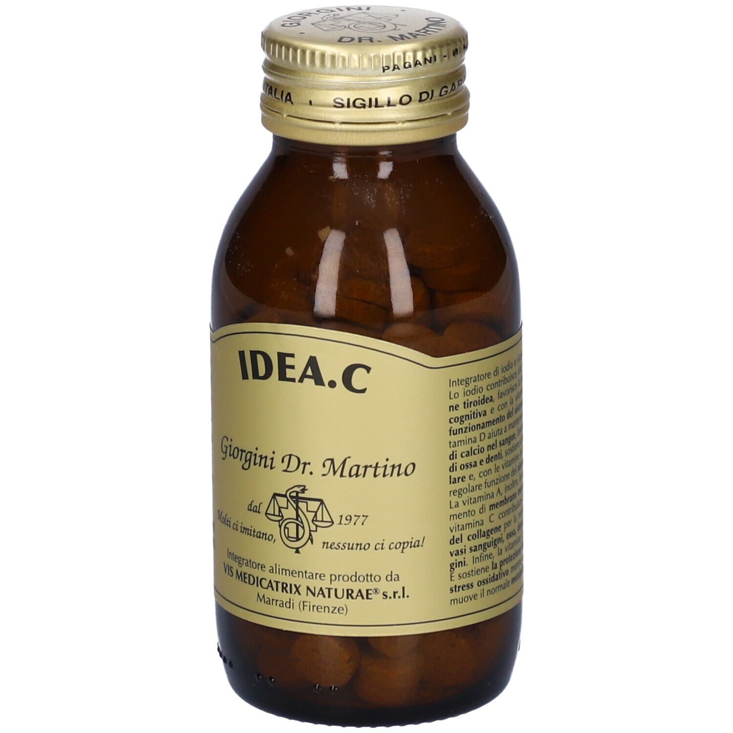 Flacone di vetro marrone con tappo dorato. Etichetta con nome del prodotto e testo. Compresse visibili.