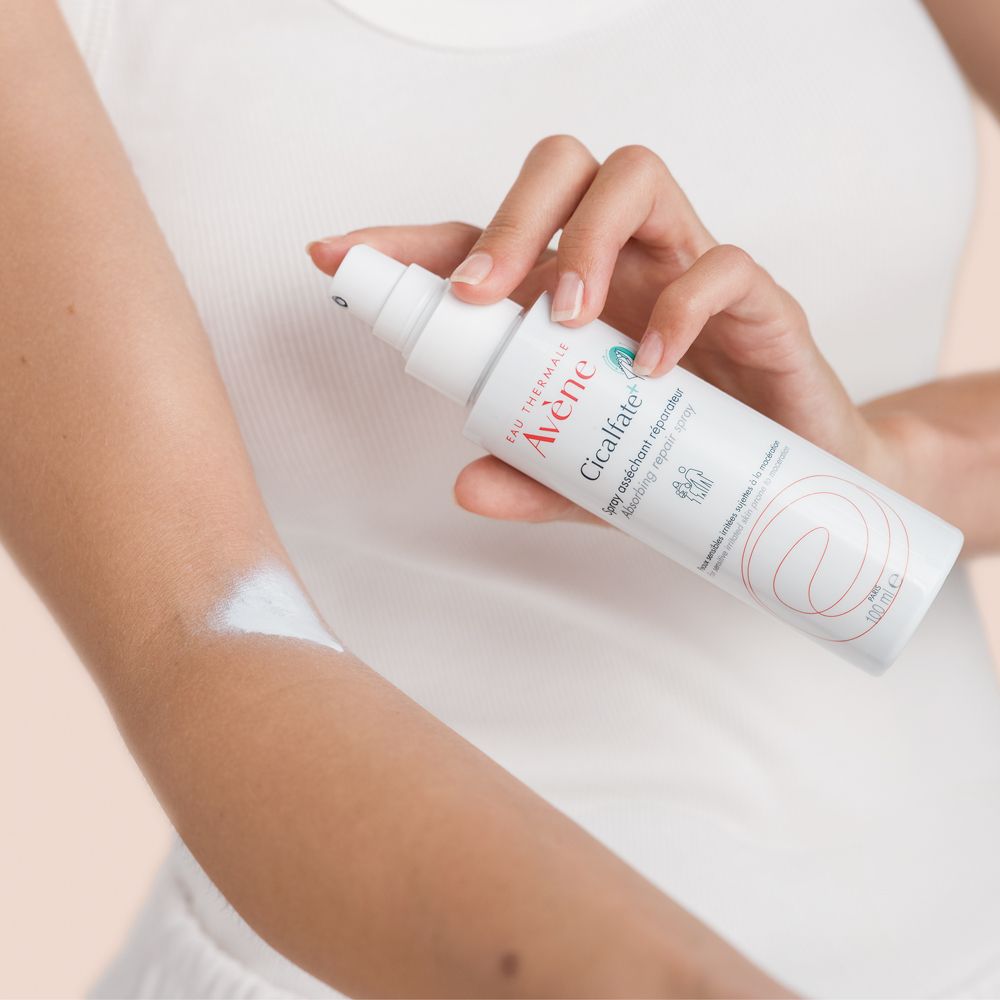 Persona tiene spray bianco Eau Thermale Avène. Cicalfate+. Spruzza sul braccio. Per pelli sensibili.