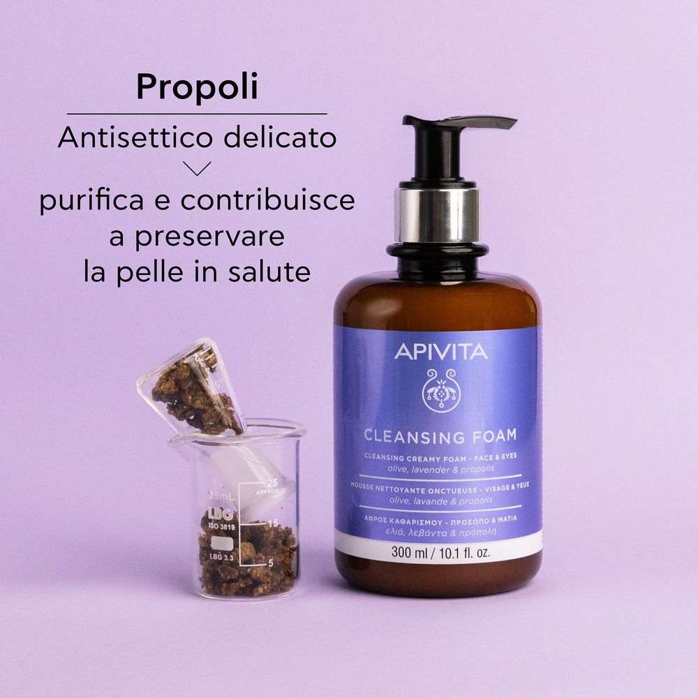 Donna che si lava il viso con Apivita Cleansing Foam. Schiuma ricca. Su sfondo viola.