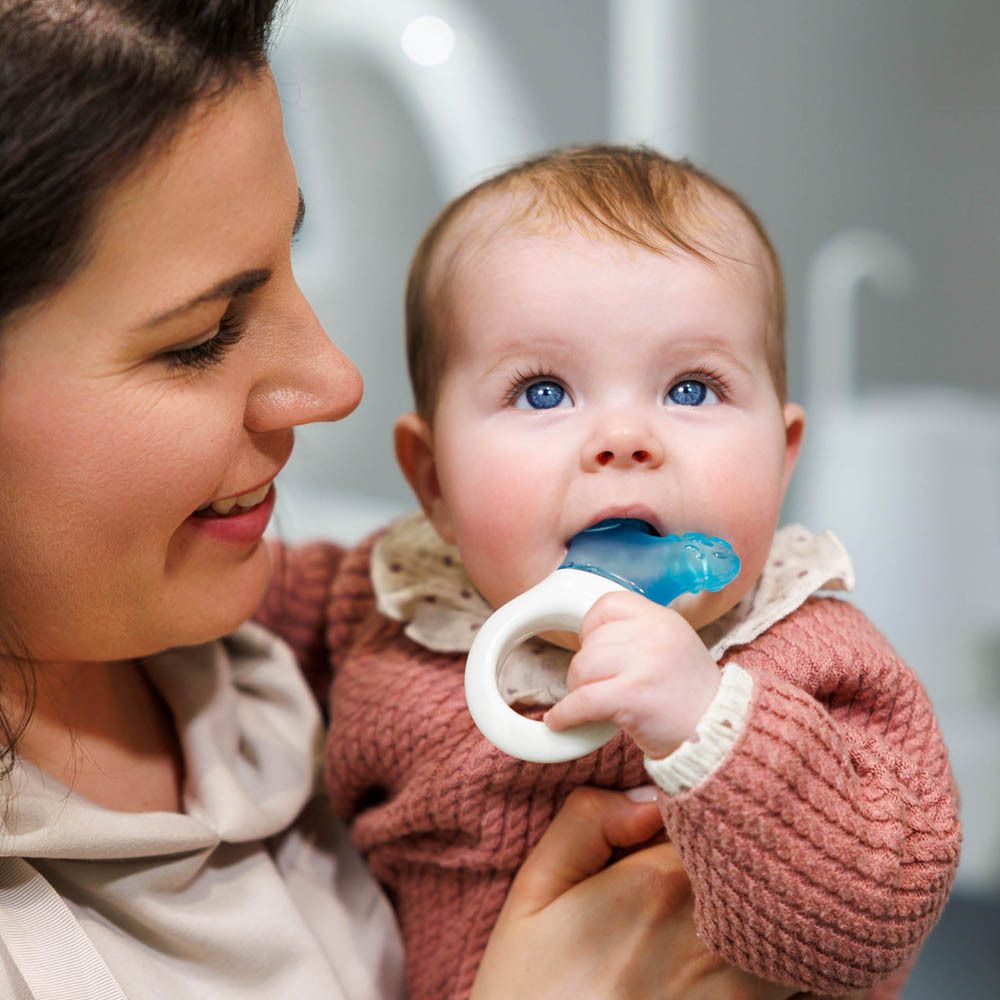 Una donna che tiene un bambino con in mano un massaggiagengive blu.