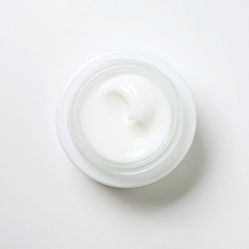 Vaso bianco con crema. Superficie della crema con struttura ondulata.