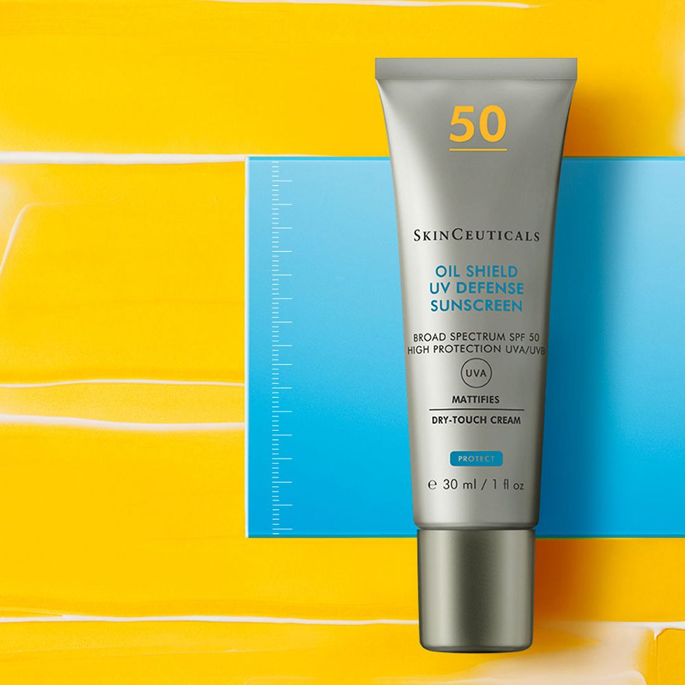 Tubo d'argento con protezione solare. Scritta: Oil Shield UV Defense Sunscreen, SPF 50. Su sfondo giallo e blu.