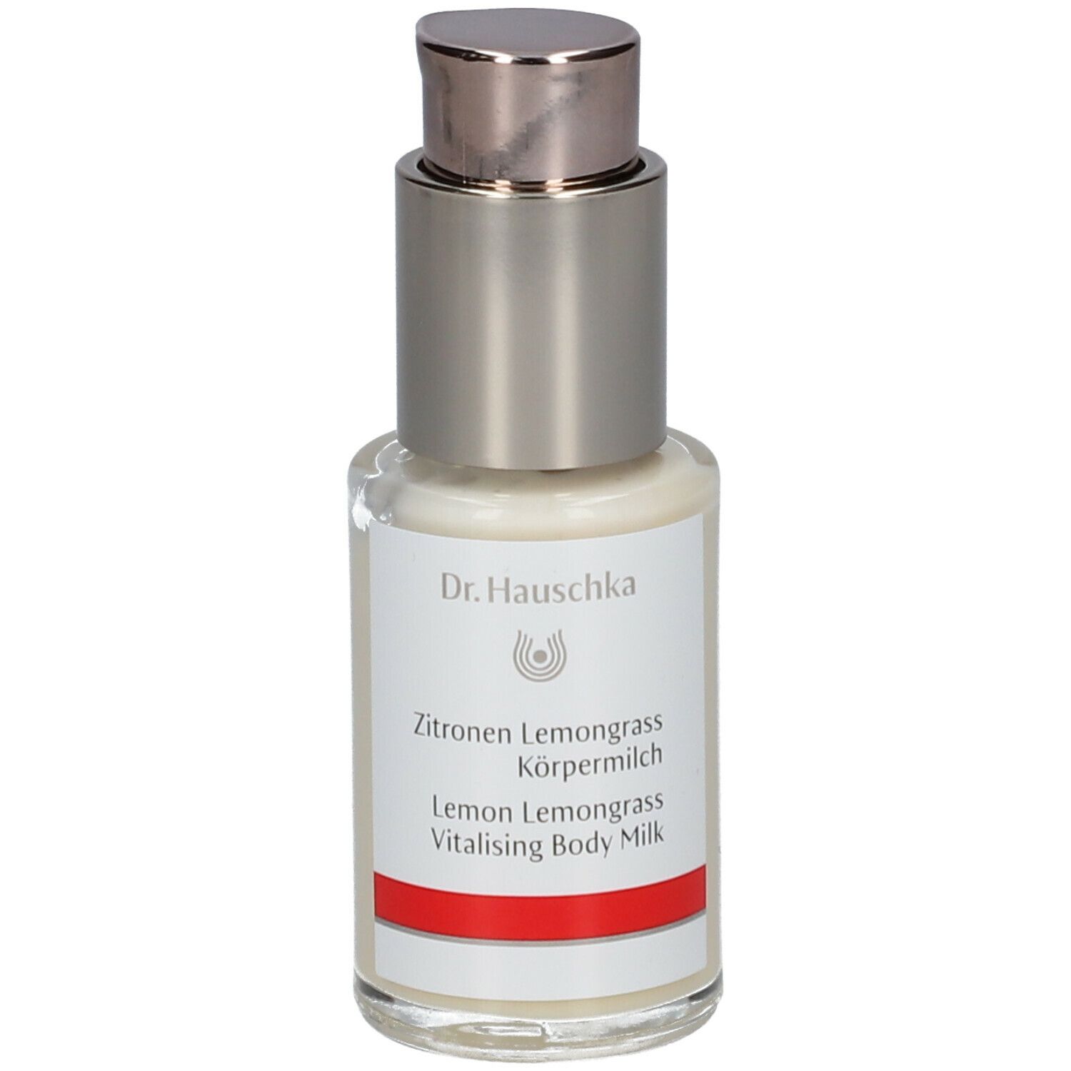 Flacone con dispenser di crema con etichetta. Scritta: Dr. Hauschka, Latte corpo Limone Lemongrass. Striscia rossa.