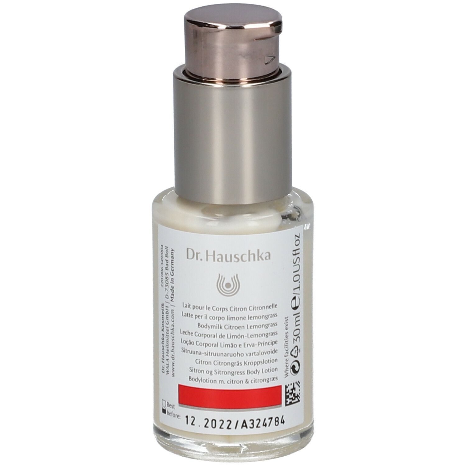 Flacone con dispenser di crema con etichetta. Scritta: Dr. Hauschka, Latte corpo Limone Lemongrass. Striscia rossa.