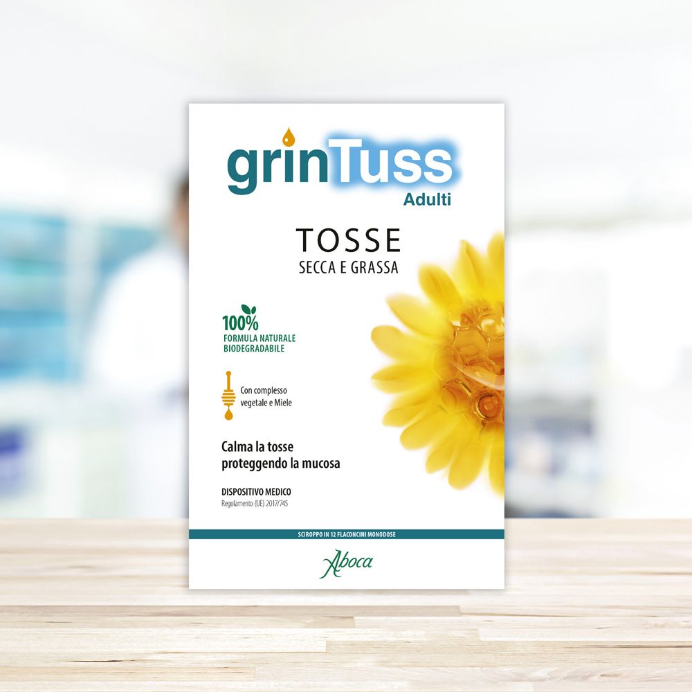 Scatola Grintuss Adulti. Scritto: Tosse Secca e Grassa. Fiore giallo. Dispositivo medico. Sfondo sfocato.