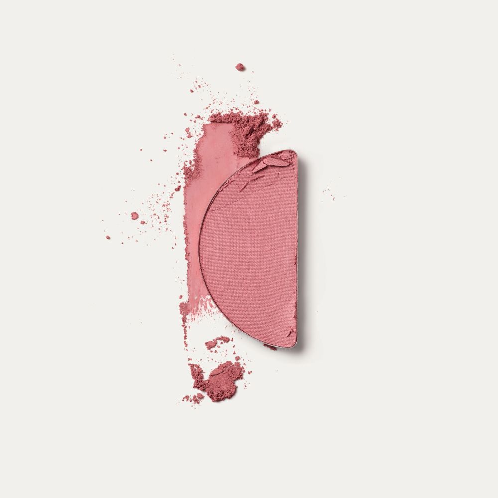 Strisciata di fard rosa. Frammenti di polvere. Su sfondo bianco.