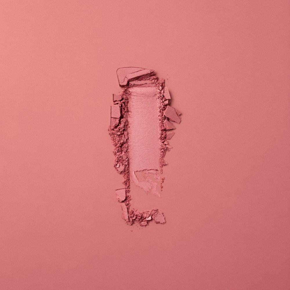 Strisciata di fard rosa. Frammenti di polvere. Su sfondo rosa.