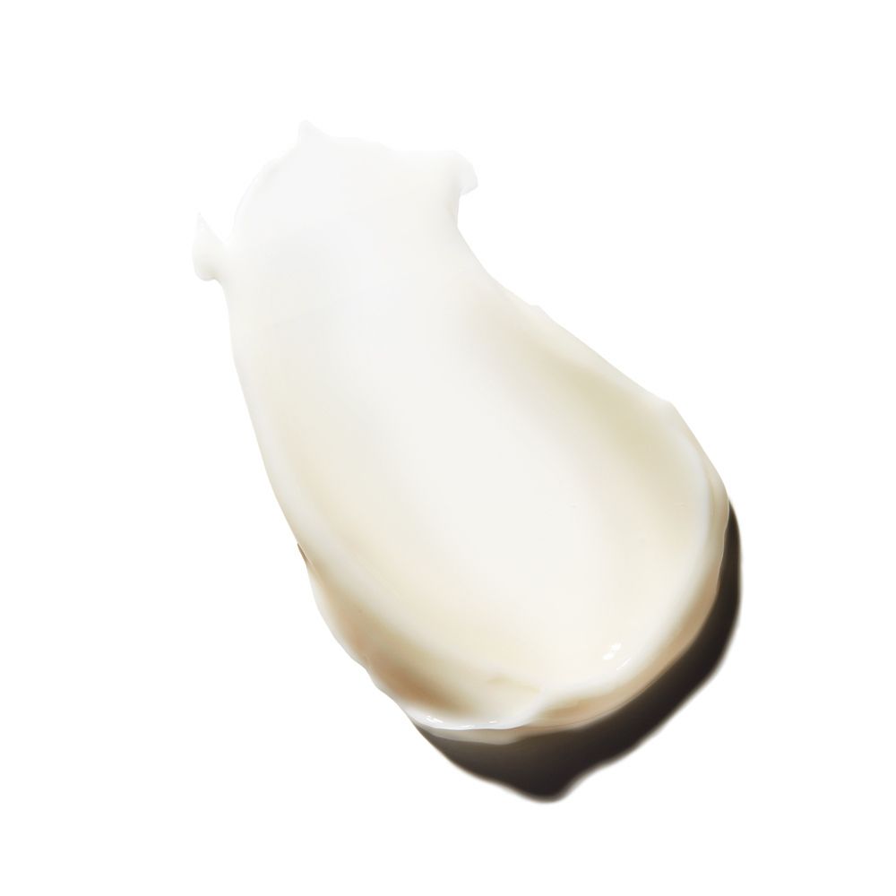 Texture di crema biancastra su sfondo bianco. La crema è applicata in forma allungata.