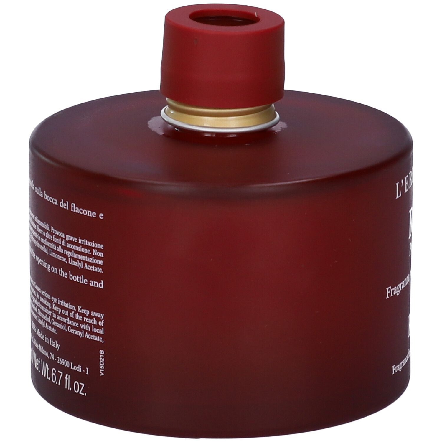 Flacone bordeaux con tappo rosso. Testo laterale. Etichetta con ingredienti e avvertenze.