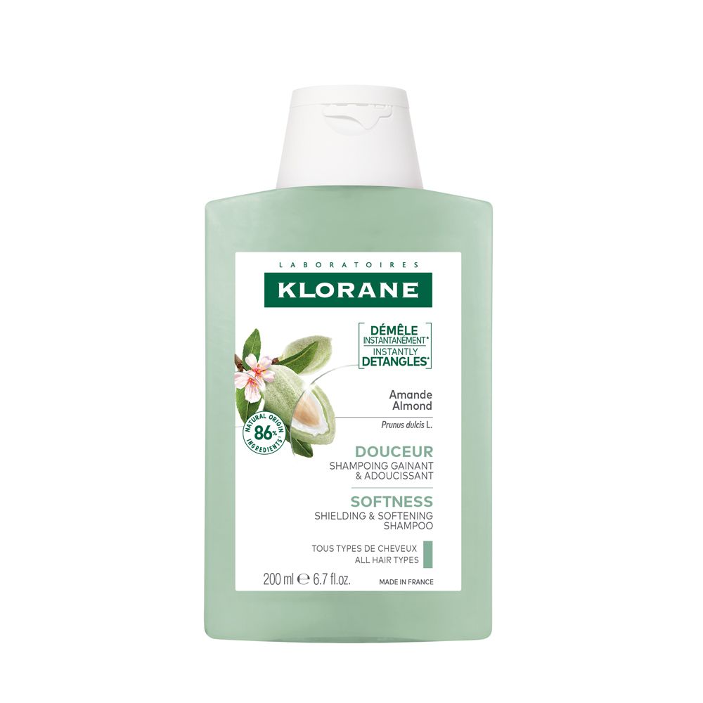 Bottiglia di shampoo verde con tappo bianco. Logo: Klorane. Testo: Mandorla, morbidezza, 200 ml, 6.7 fl. oz. Illustrazione fiore e mandorla.