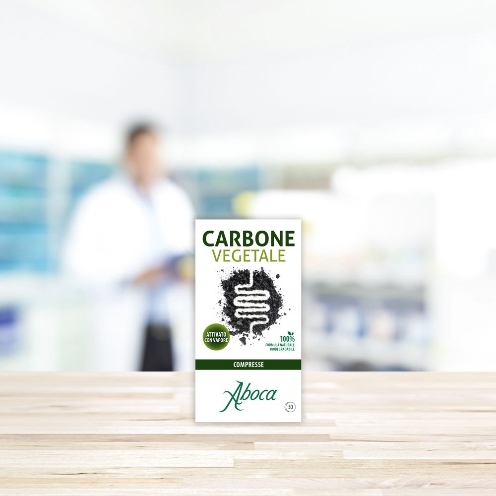 Aboca Carbone Vegetale 30 Compresse su un tavolo di legno. Sfondo sfocato di una scena di farmacia.