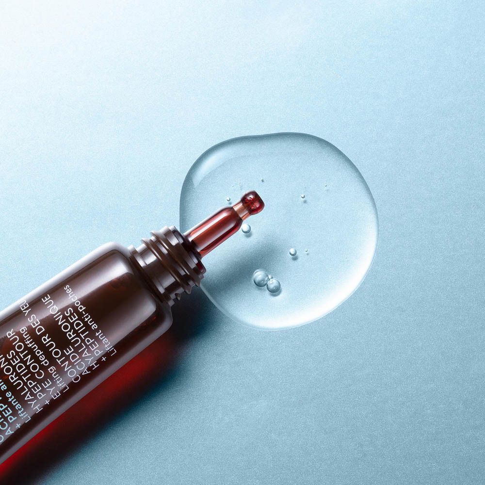 Goccia di liquido trasparente. Applicatore marrone. Sfondo azzurro.