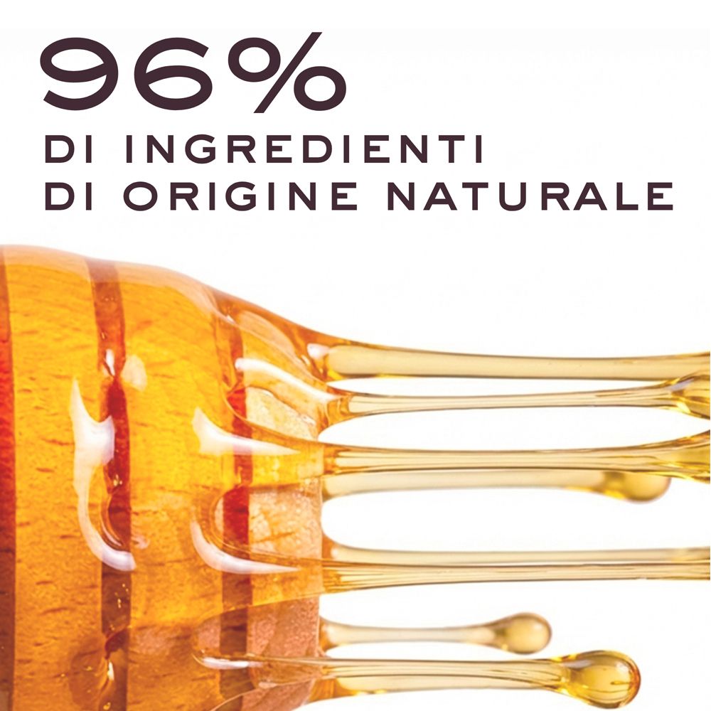 96% di ingredienti di origine naturale. Miele che cola su sfondo bianco.