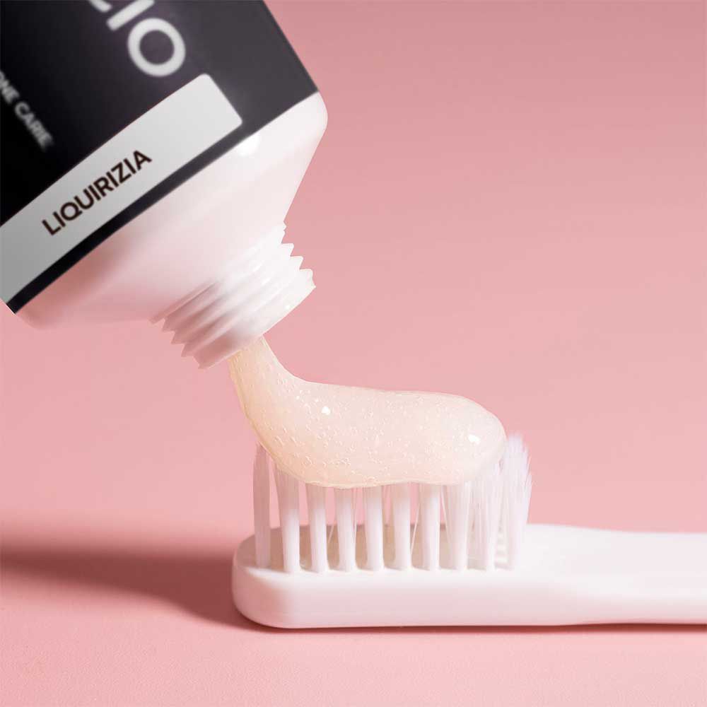 Dentifricio spremuto su uno spazzolino. Sfondo rosa. Spazzolino bianco.