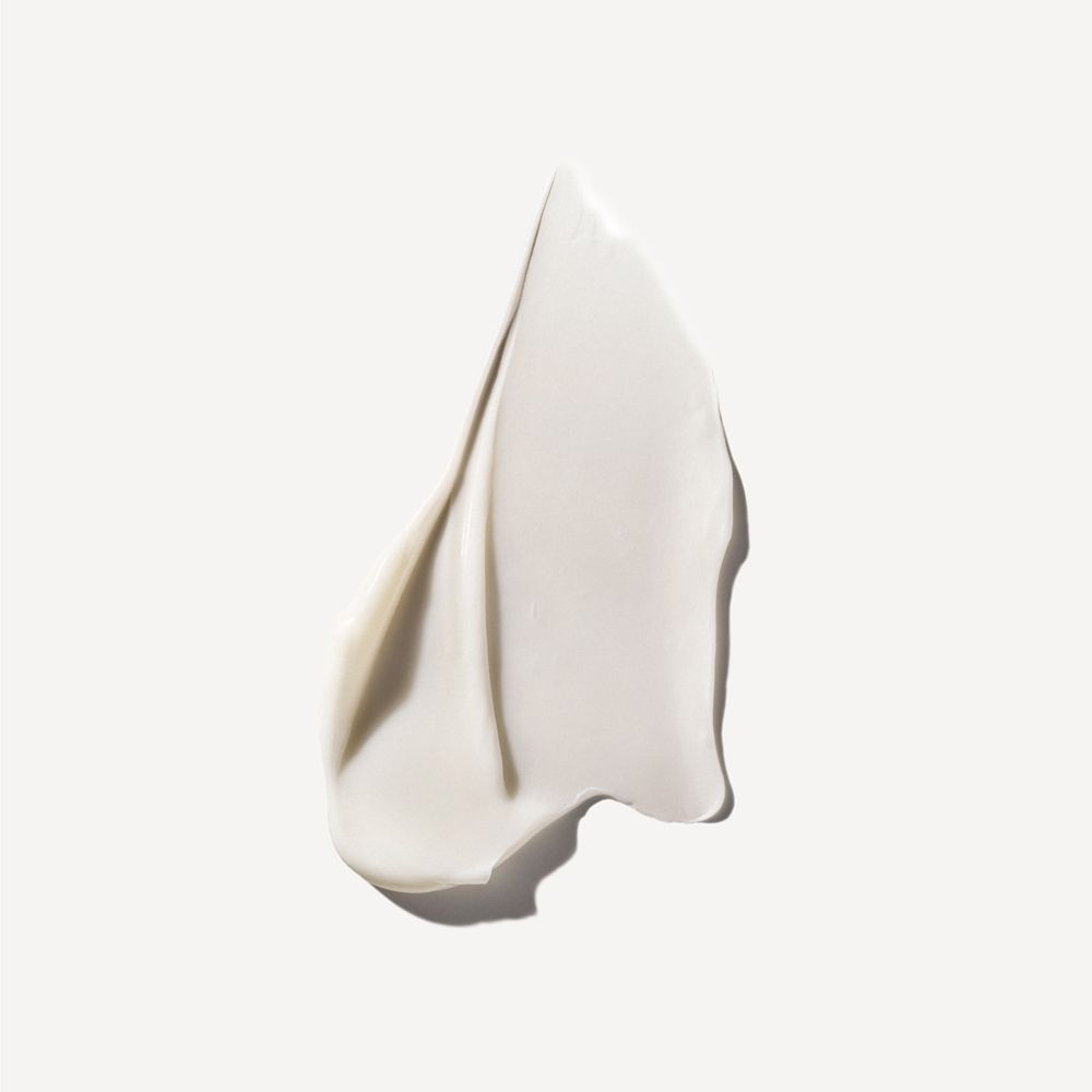 Primo piano di una sostanza cremosa bianca. Consistenza simile a una crema o un balsamo. Su sfondo chiaro.