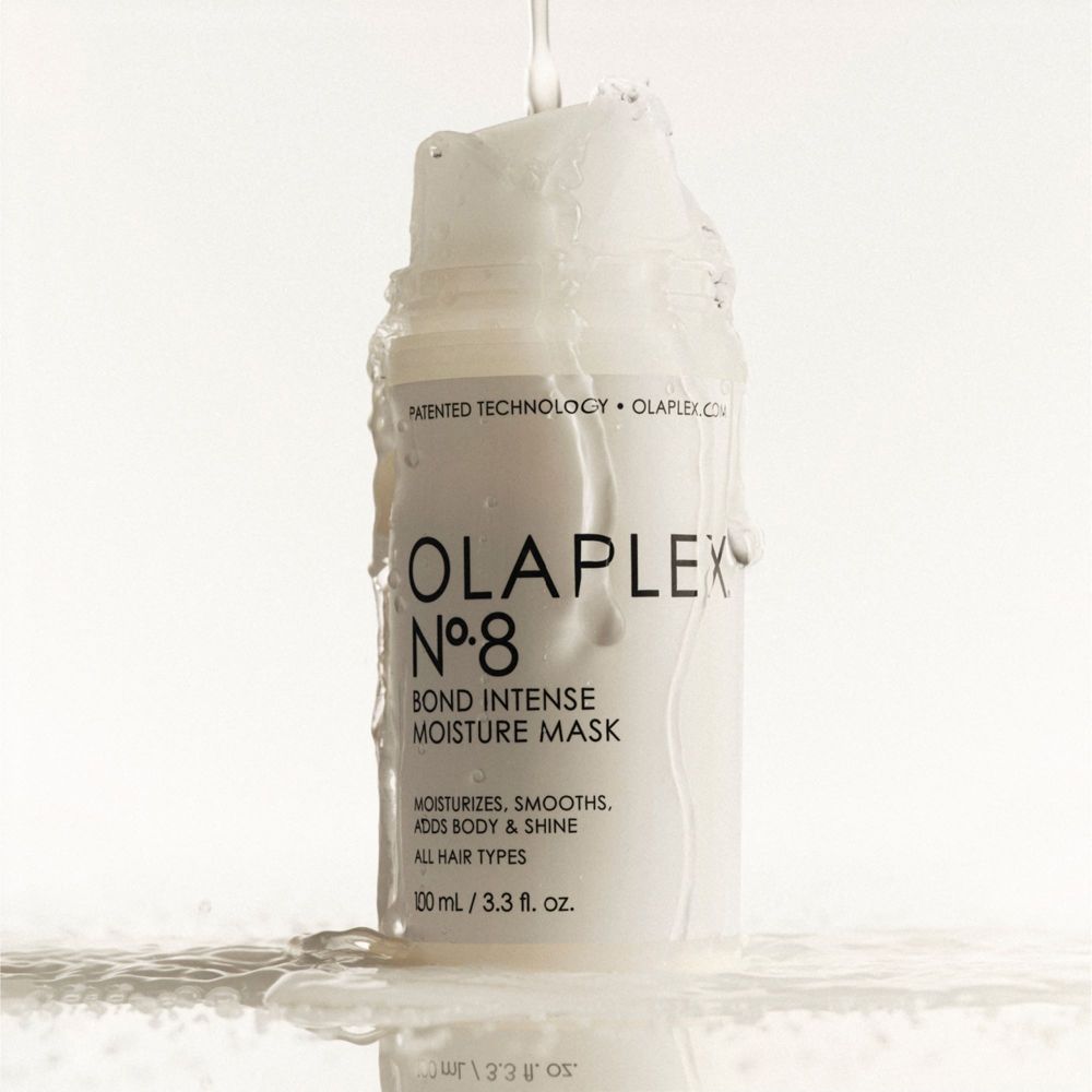 Flacone bianco con tappo a ribalta. L'acqua scorre sul flacone. Scritta: Olaplex Nr. 8 Bond Intense Moisture Mask.
