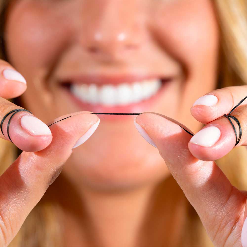 Mani che tengono un filo nero. Sorriso. Unghie smaltate. Filo teso.