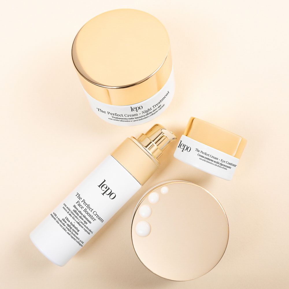 Tre prodotti cosmetici: booster viso, crema notte e contorno occhi. Tappi dorati, flaconi bianchi. Nomi dei prodotti visibili.