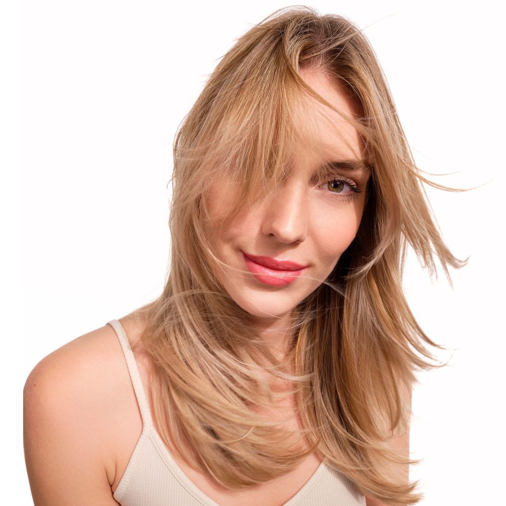 Ritratto di una donna con capelli biondi. Indossa un top bianco.
