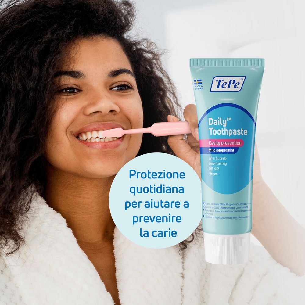 Donna si lava i denti con dentifricio TePe Daily, menta delicata, per la prevenzione della carie.