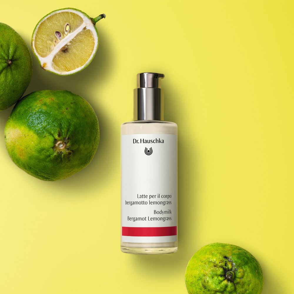 Lozione per il corpo con lime verdi su sfondo giallo. Scritta: Dr. Hauschka, Latte per il corpo, Bergamotto Lemongrass.