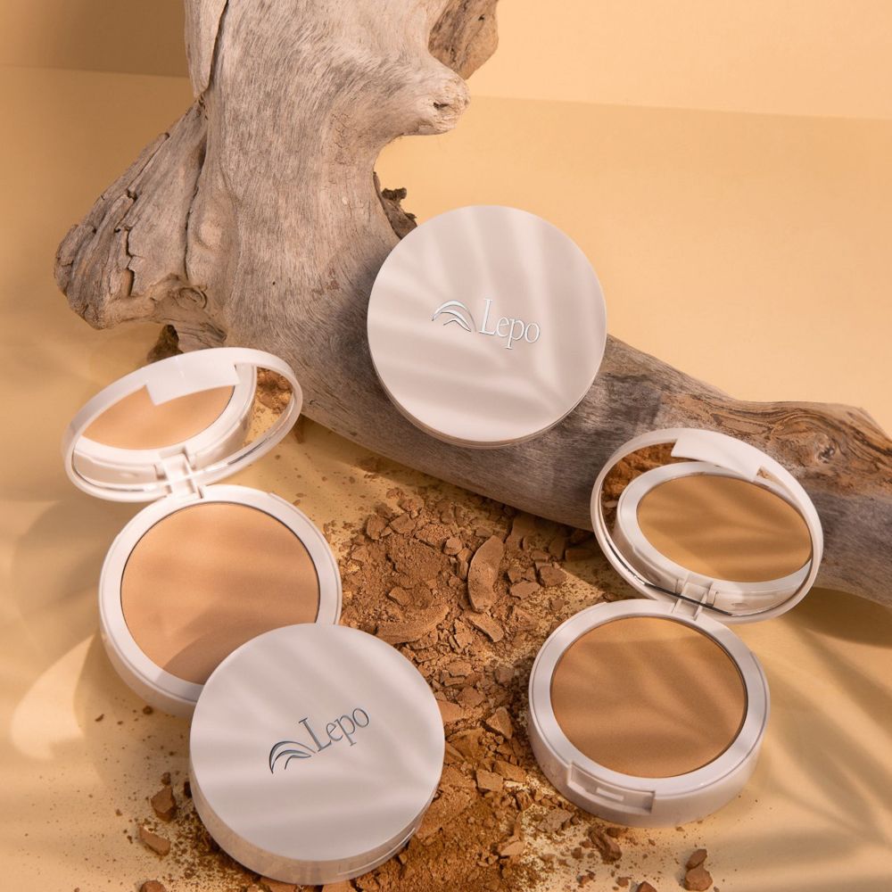 Tre fondotinta compatti aperti. Polvere beige chiaro. Marchio Lepo. Legno e foglie.