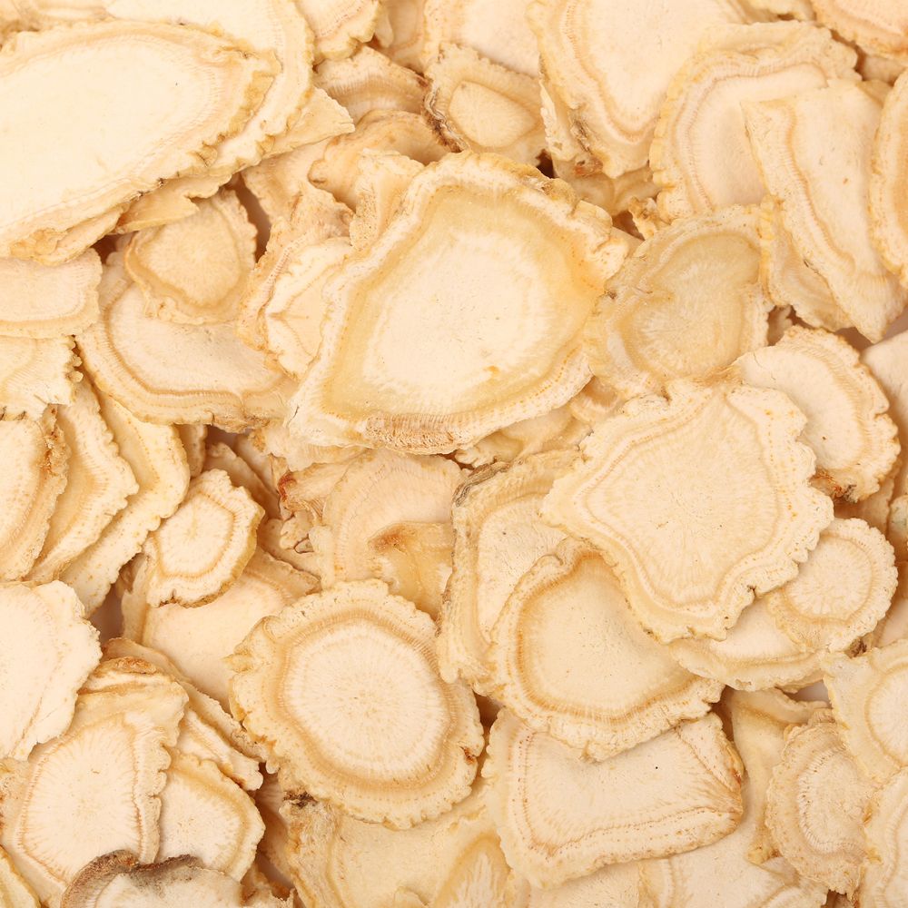 Primo piano di fette di ginseng essiccate. Colore marrone chiaro, forma irregolare, consistenza visibile.