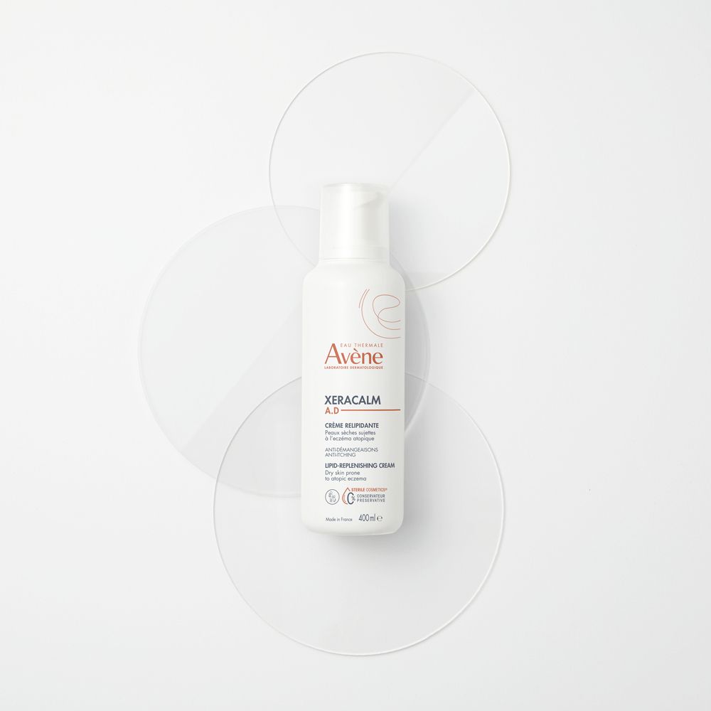 Avène XeraCalm A.D. Crema su cerchi trasparenti. Flacone bianco con dosatore.