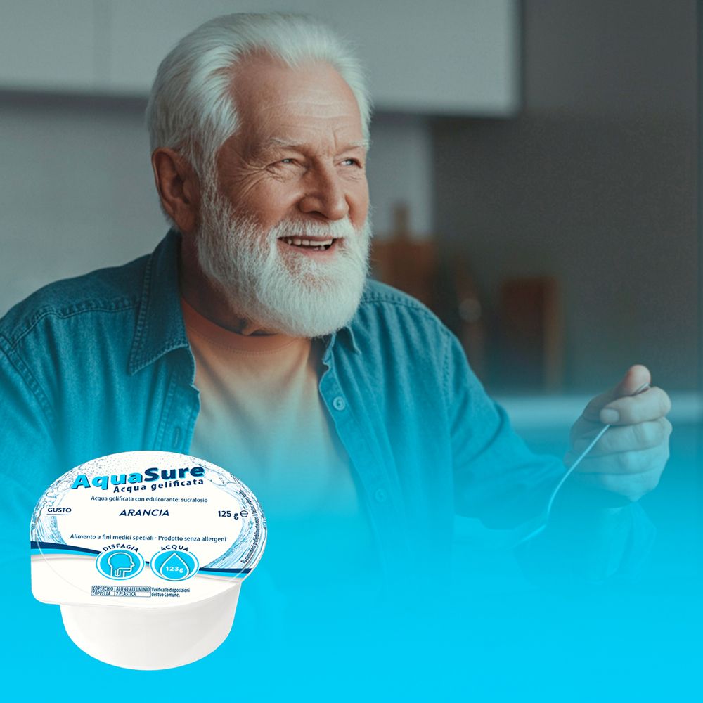 Uomo anziano sorridente. Davanti a lui, una coppa AquaSure con arance. Sfondo blu.