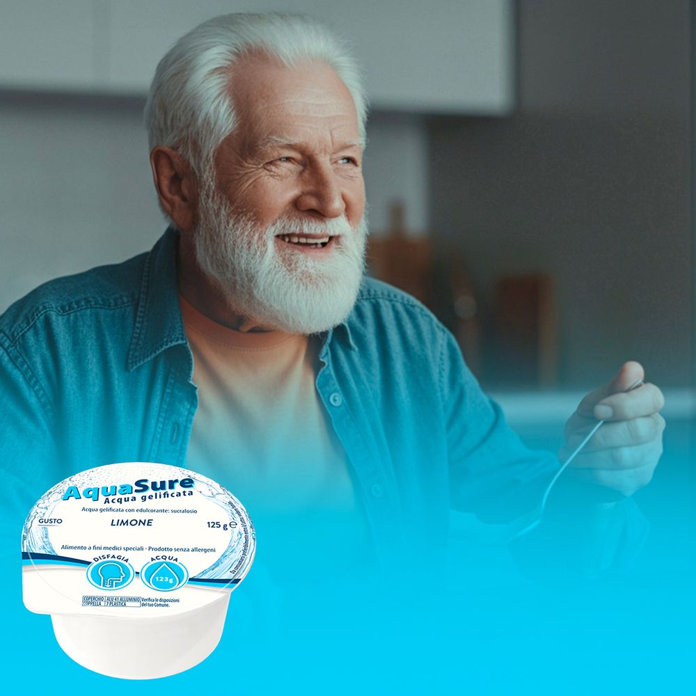 Uomo anziano sorridente. Davanti a lui, una porzione di AquaSure Acqua gelificata gusto Limone.