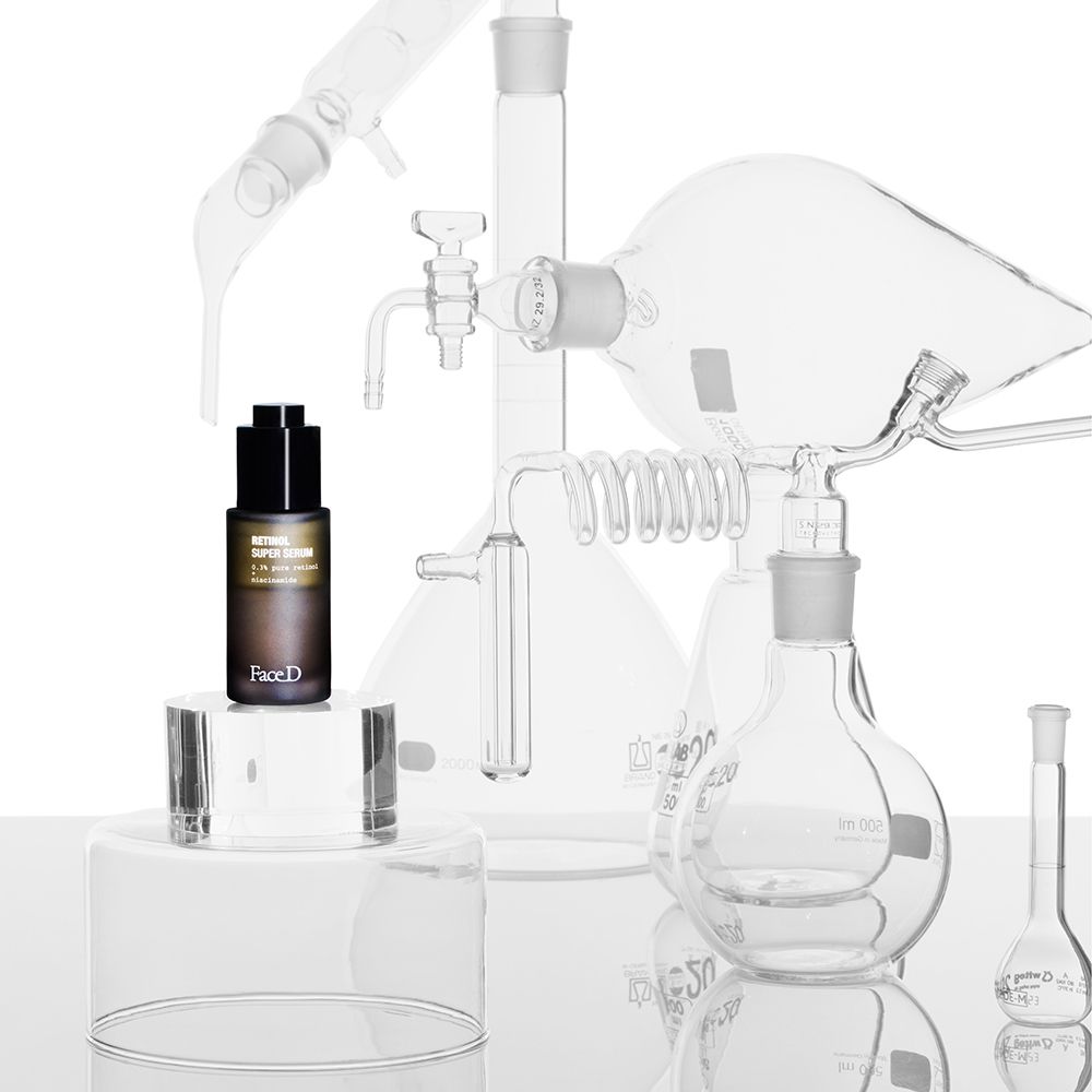 Flacone marrone con tappo nero su piedistallo. Vetreria da laboratorio sullo sfondo. Scritta: Retinol Super Serum. Face D.
