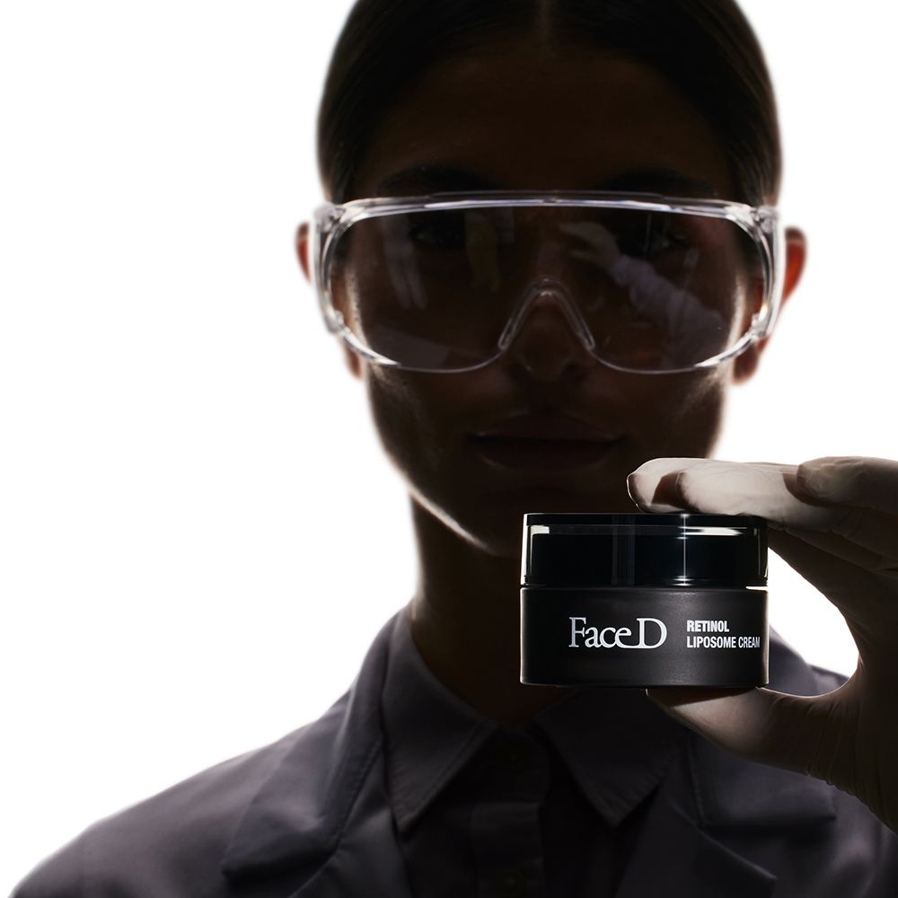 Persona che tiene un vasetto di Face D Retinol Liposome Cream. Indossa occhiali.