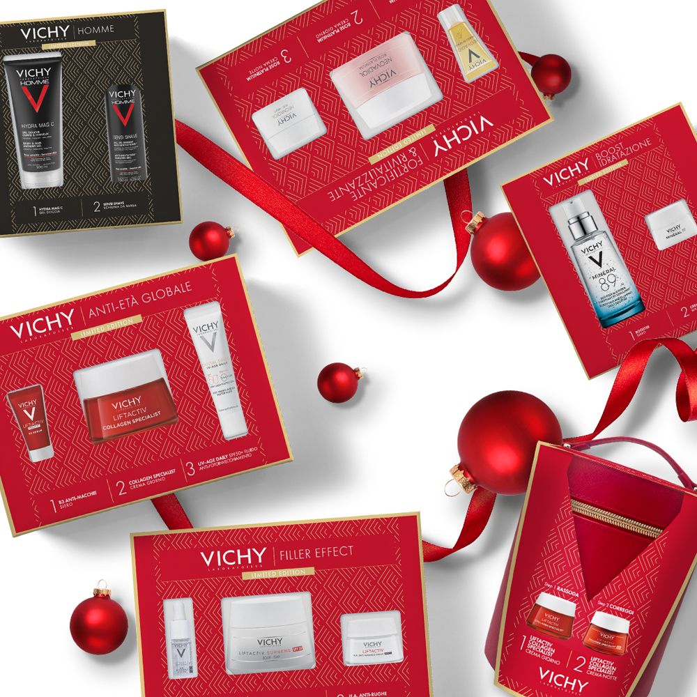 Diverse confezioni regalo Vichy con prodotti vari. Scatole rosse con fiocchi e decorazioni natalizie.