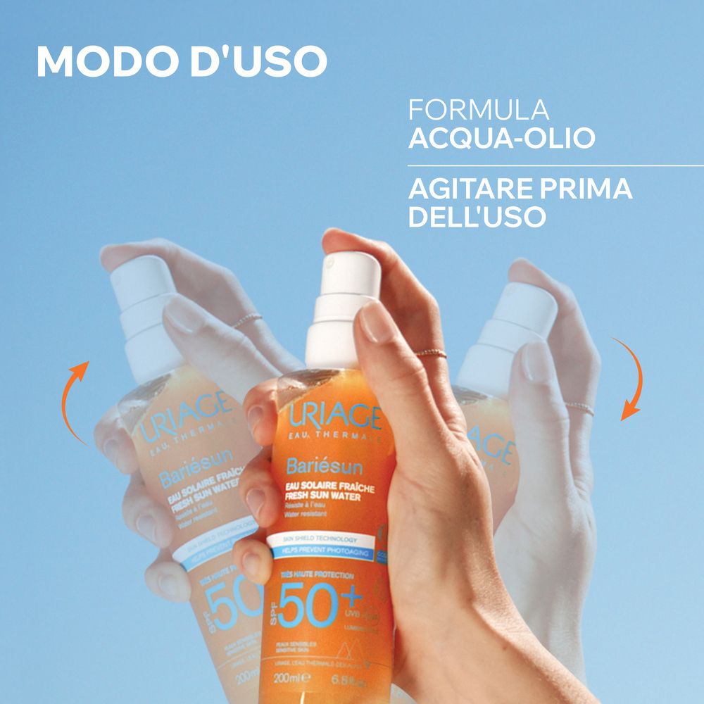 Mani che agitano lo spray Uriage Bariésun. Testo: Formula acqua-olio, agitare prima dell'uso.