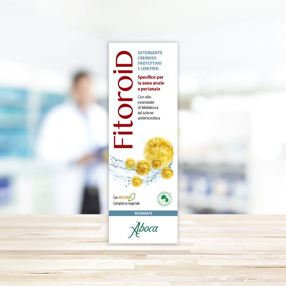 Confezione del prodotto con logo Fitoroid. Sfondo: persona sfocata in camice bianco.