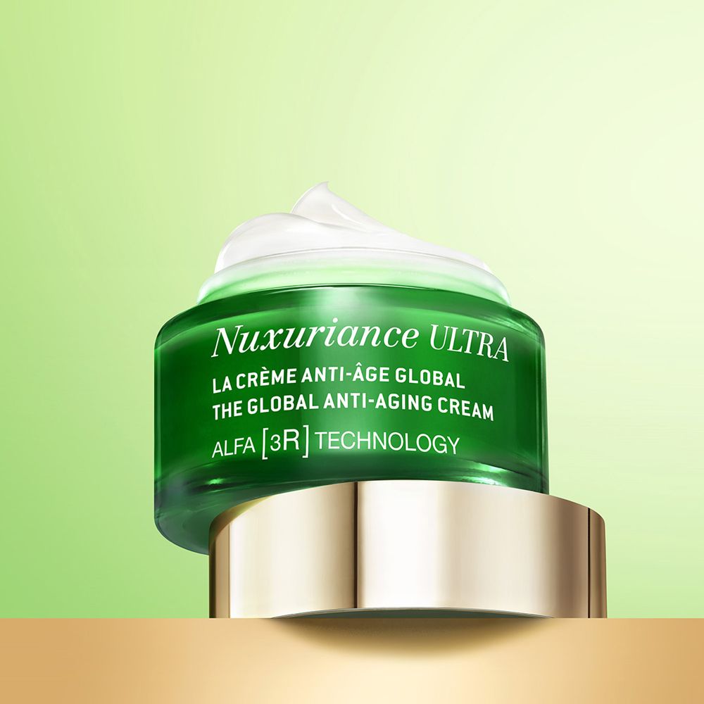 Vasetto verde con crema. Scritta: Nuxuriance Ultra, La Crème Anti-Âge Global. Logo albero. Coperchio dorato.
